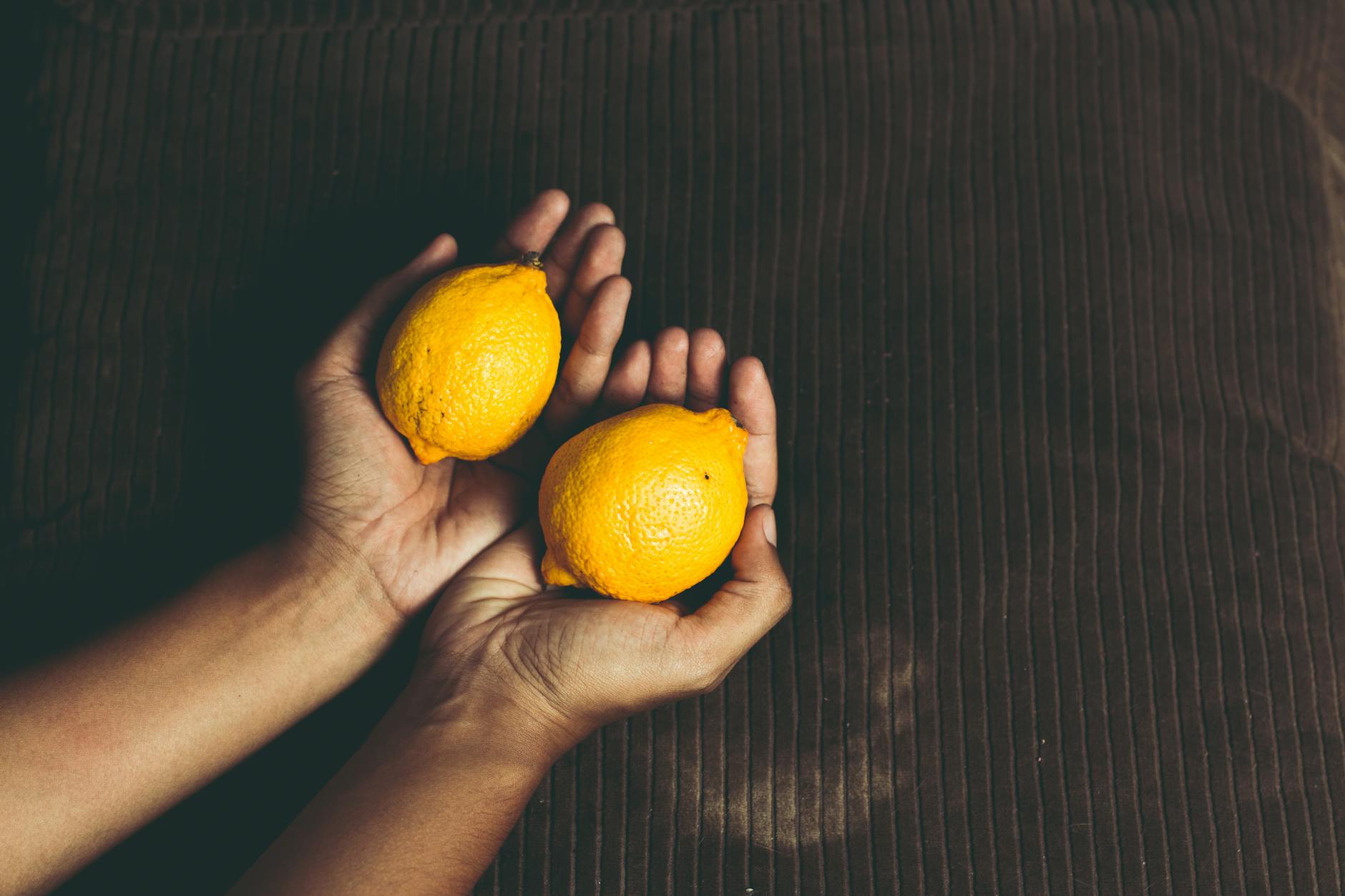 Fresh lemons in cupped hands symbolizing comfort and wellness