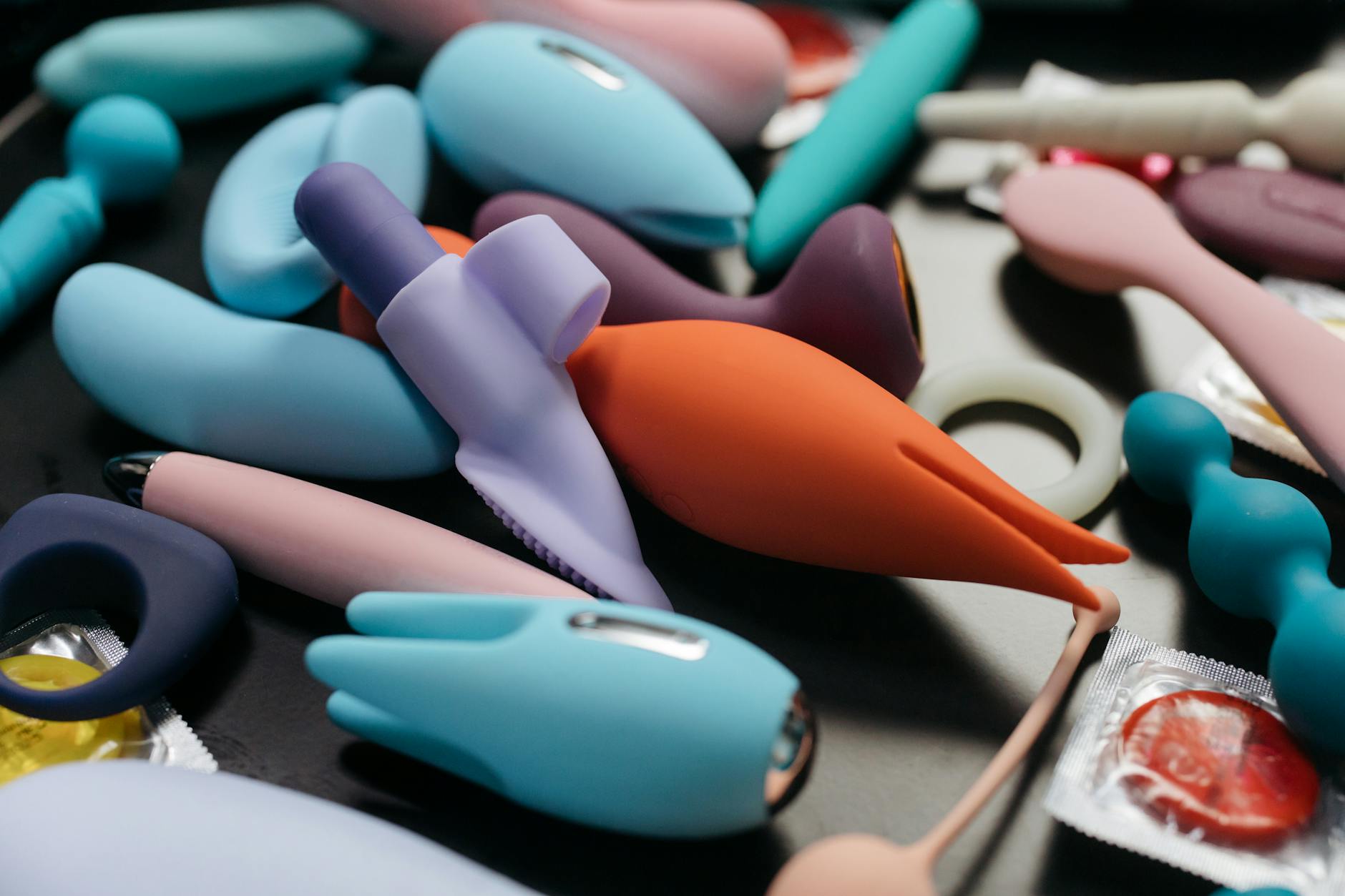 Array of colorful adult toys arranged on a yellow background