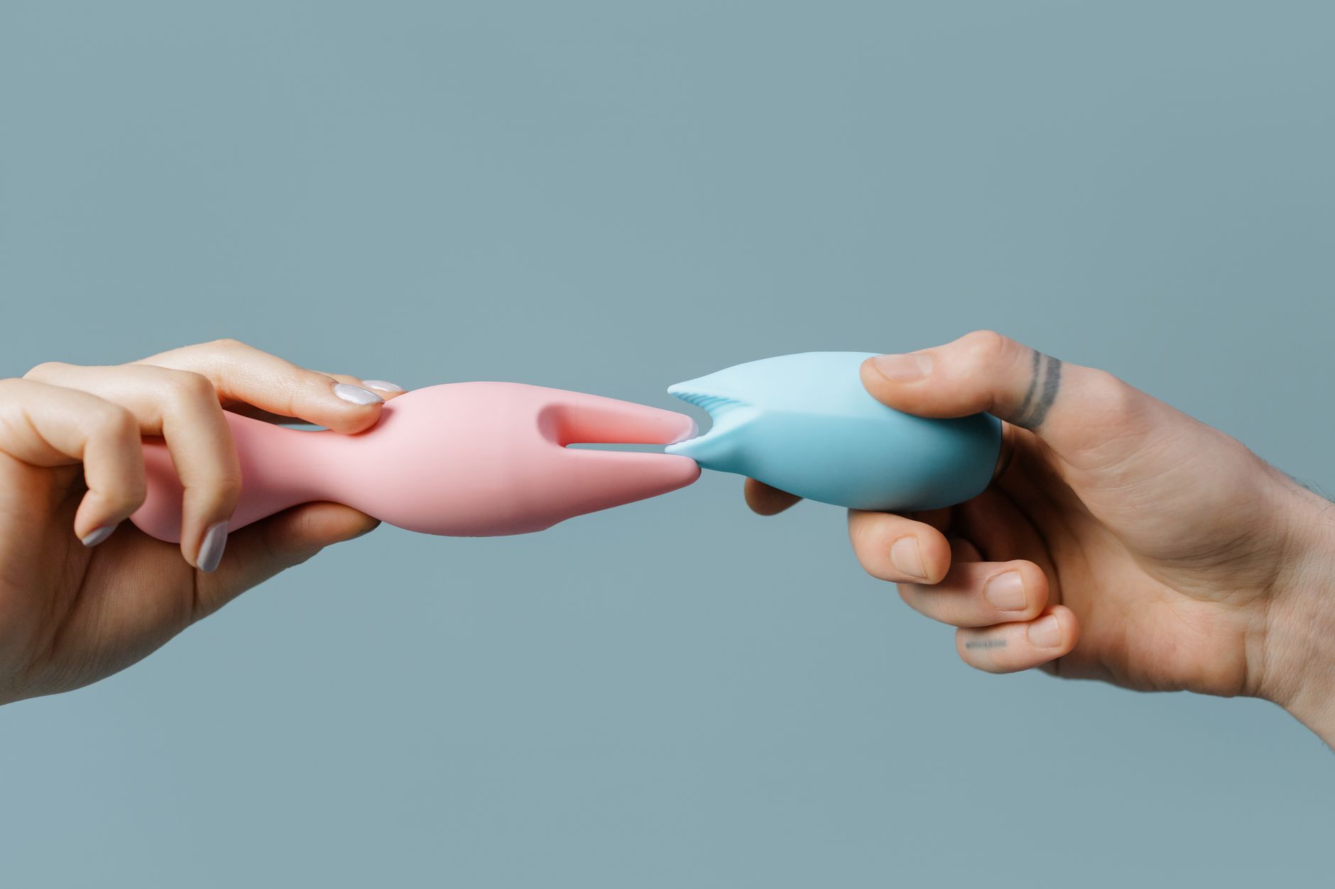 Close-up of a woman holding a pink vibrator with art books in the background