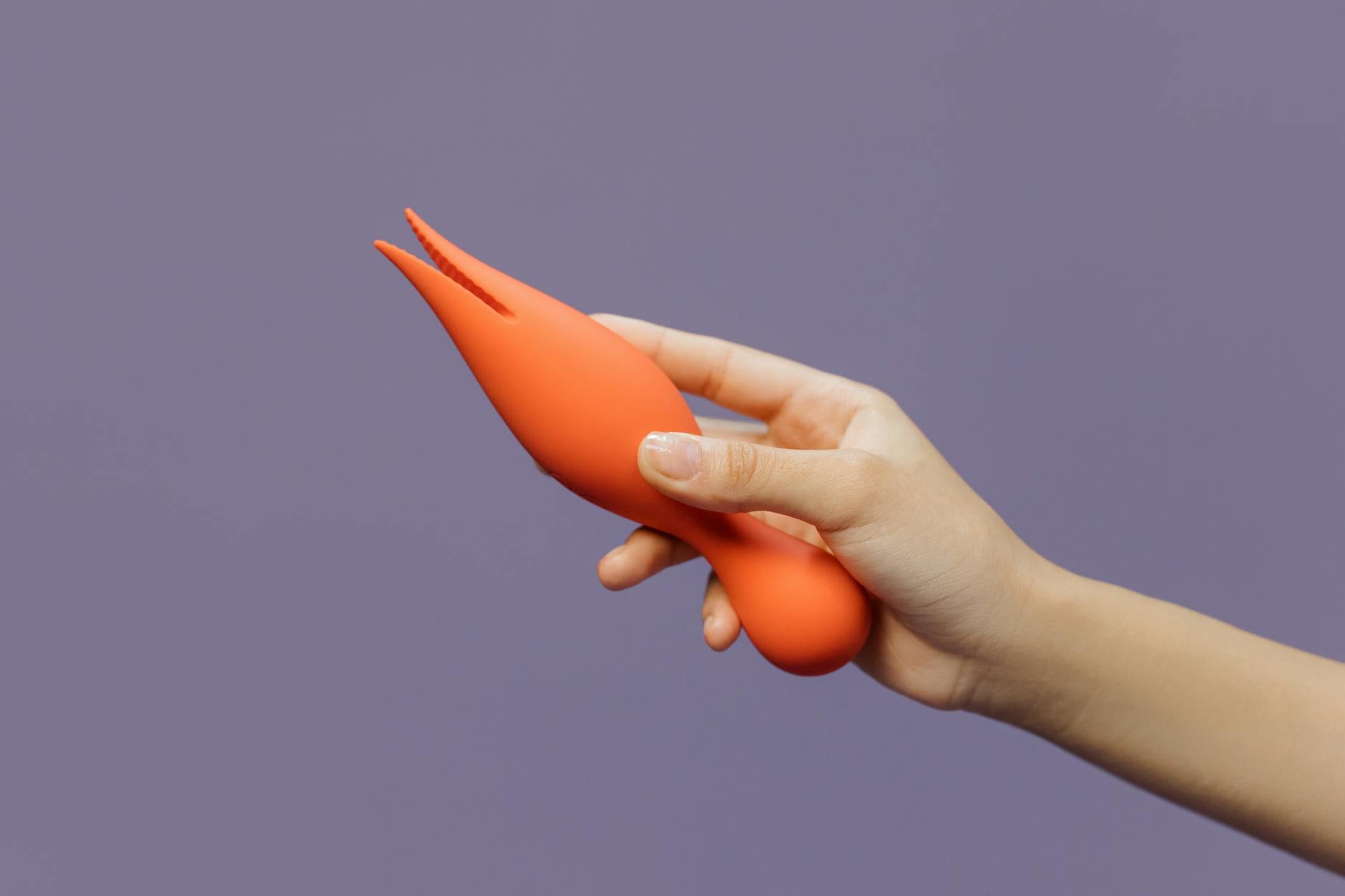 Hand holding a lemon vibrator against a minimalist purple background, representing modern sensuality and self-care.