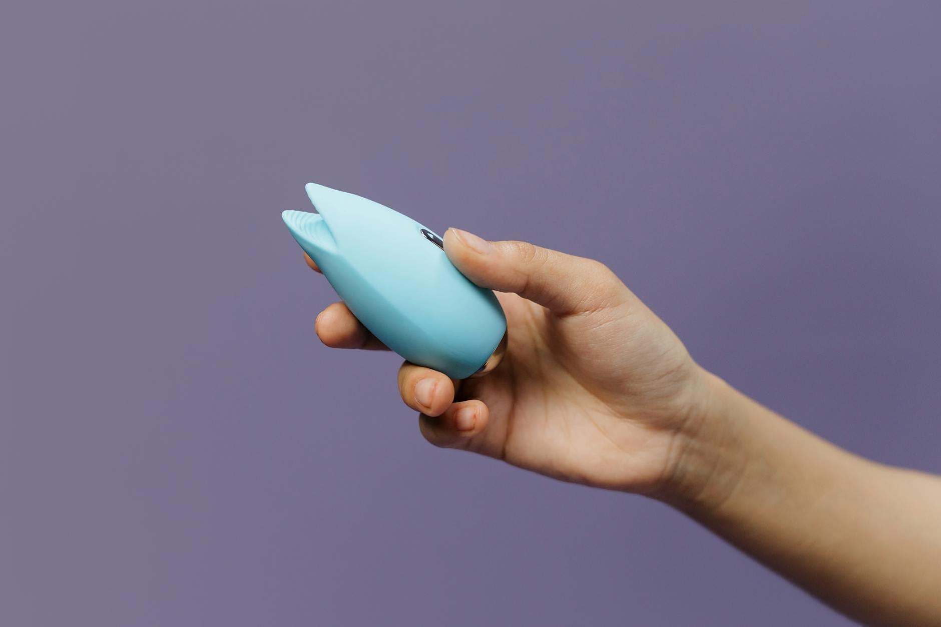 A lemon vibrator held gently in hand against a calm purple background, symbolizing self-compassion and pleasure reclamation