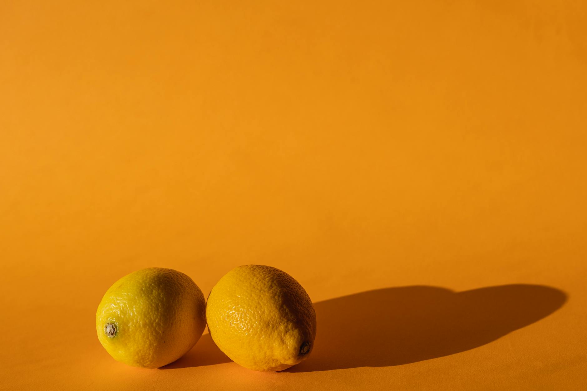 Ripe vivid lemons on bright yellow background in studio light
